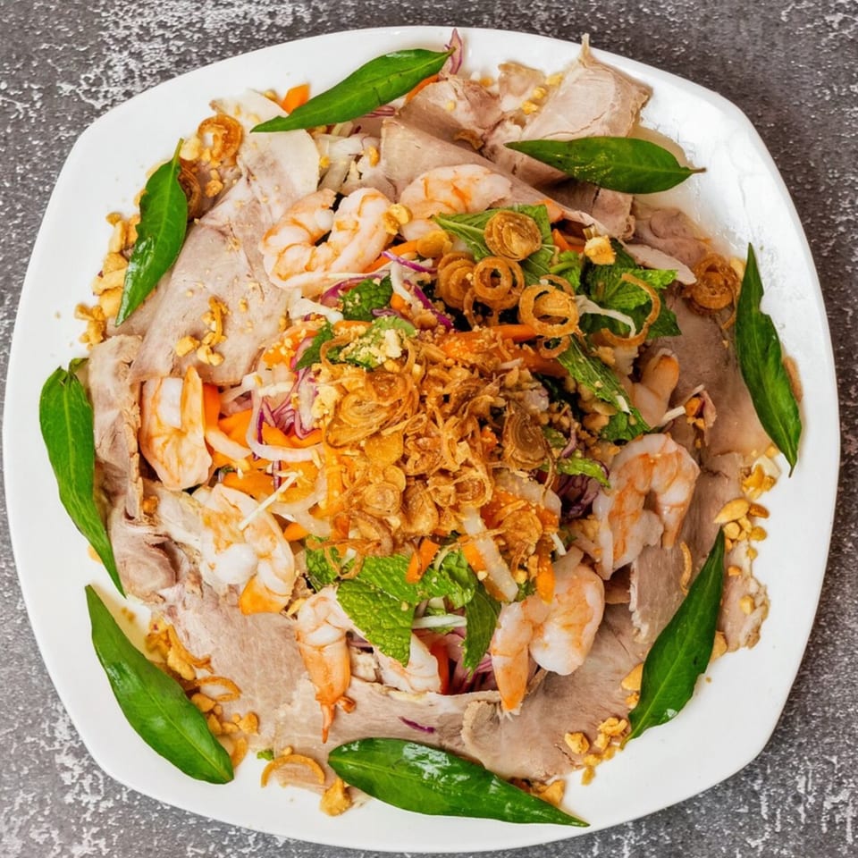 Vo An Vietnamese salad with sliced pork, shrimp, herbs, and crispy fried shallots on a white plate.