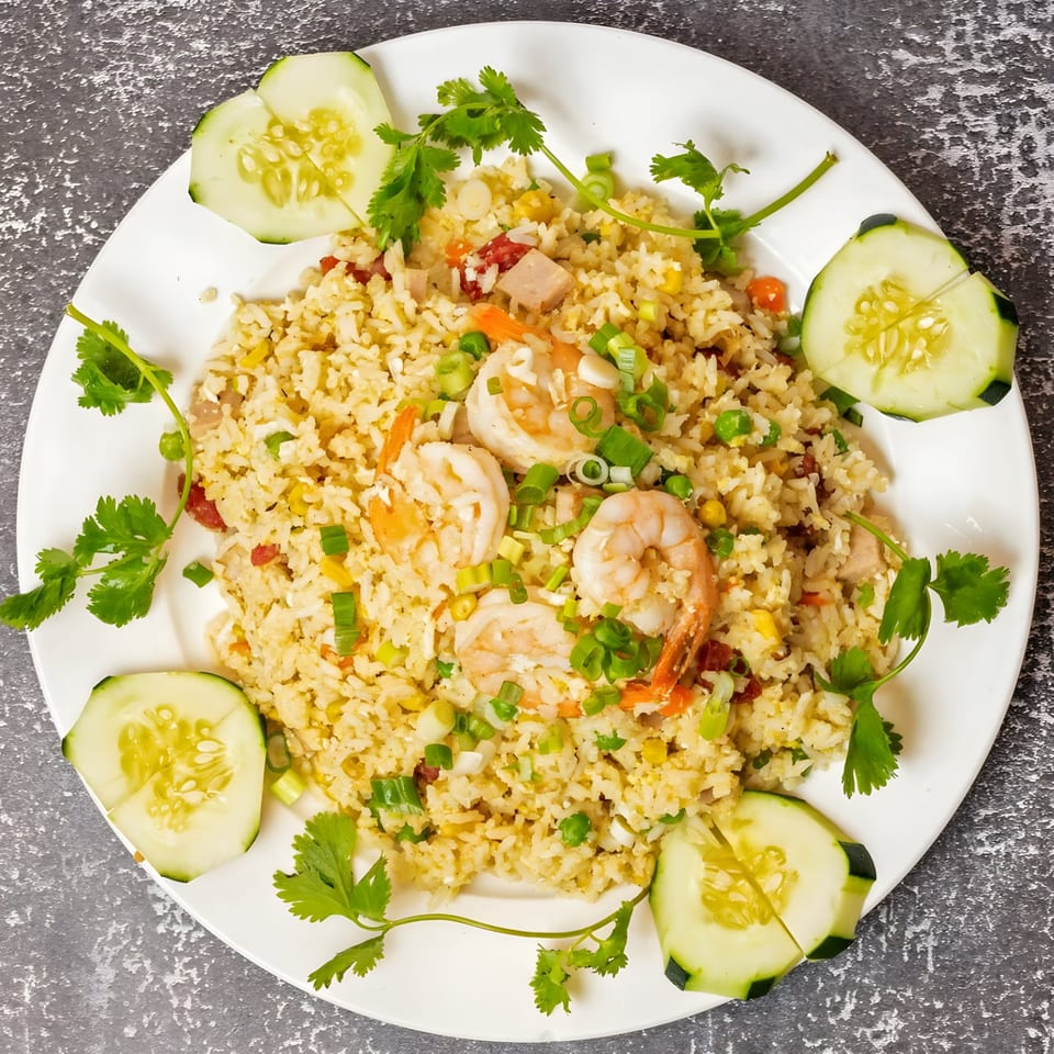 Vo An Vietnamese shrimp fried rice with vegetables, garnished with cilantro and cucumber slices.