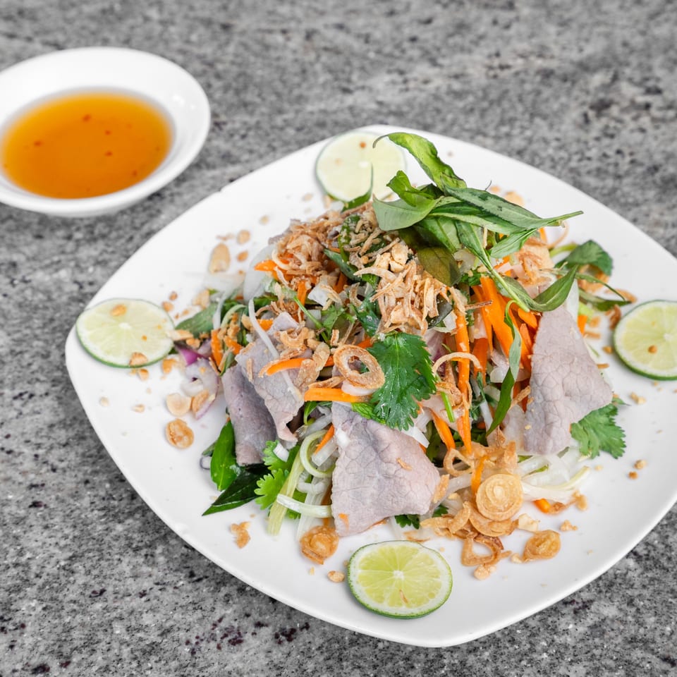 Vietnamese beef salad with herbs, carrots, fried shallots, and lime, served with dipping sauce.